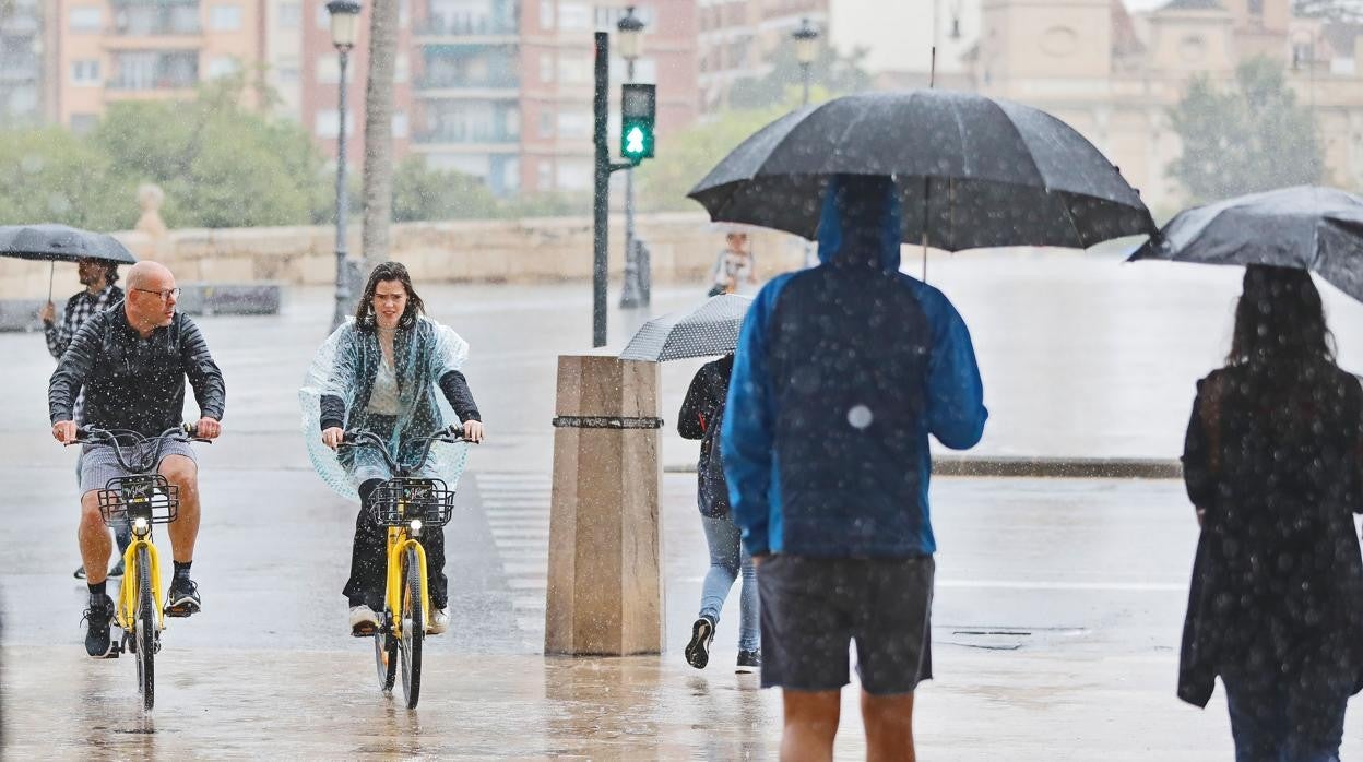 Imagen de archivo de varios ciclistas y peatones en un día de lluvia en Valencia