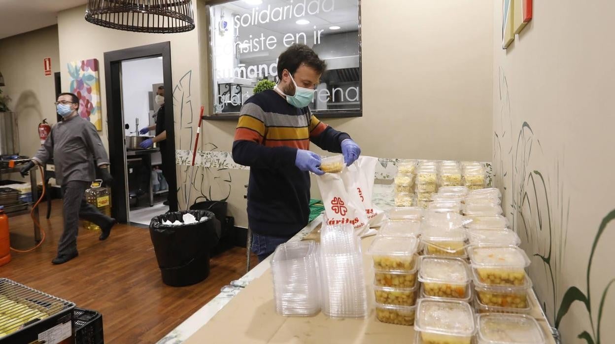 Un joven de Cáritas prepara menús para dárselos los necesitados