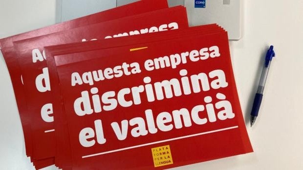 La «ONG del catalán» reparte adhesivos para señalar a las empresas que no usan el valenciano