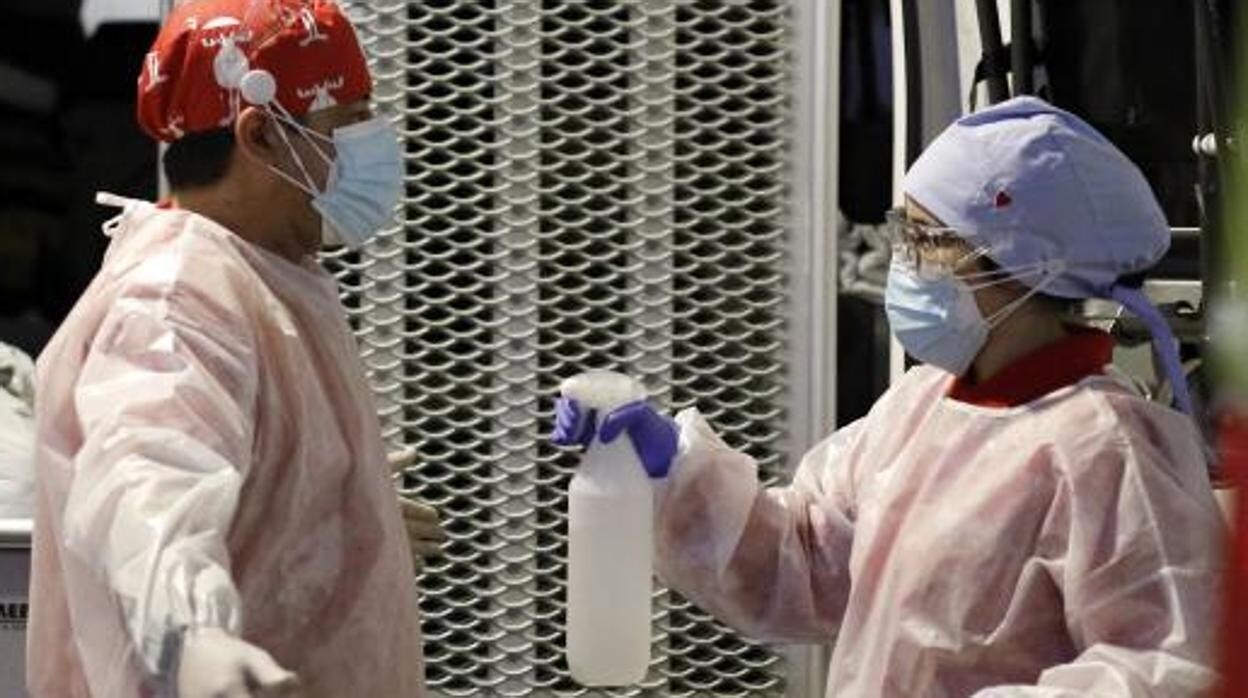 Dos sanitarios desinfectan sus equipos de protección contra el Covid