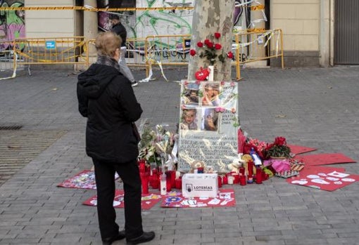 Una mujer observa el altar improvisado ante el local quemado de Tetuán