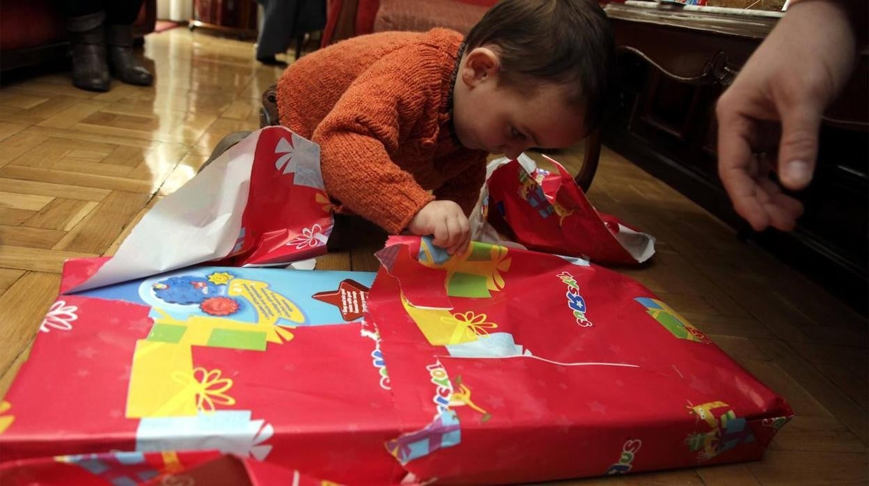 Foto de archivo de un niño abriendo un regalo de Reyes