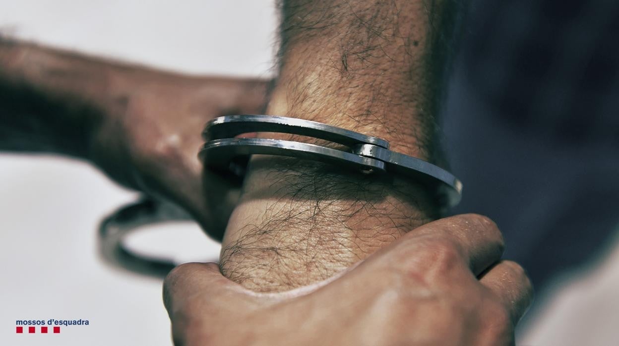 Un agente coloca las esposas a un detenido