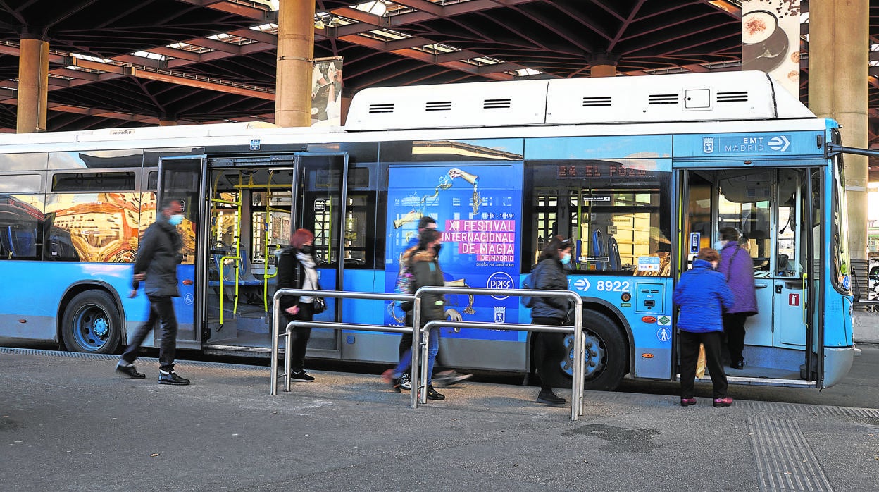 Varios viajeros suben a un autobús de la EMT en Atocha