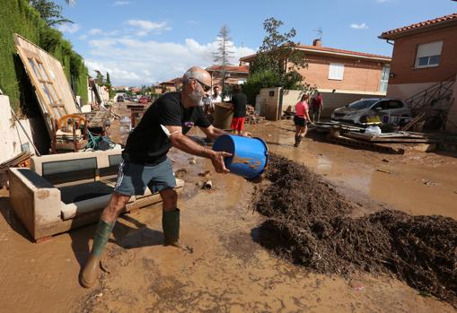 Un vecino de Cobisa (Toledo), vacía un cubo lleno del agua que inundó su vivienda