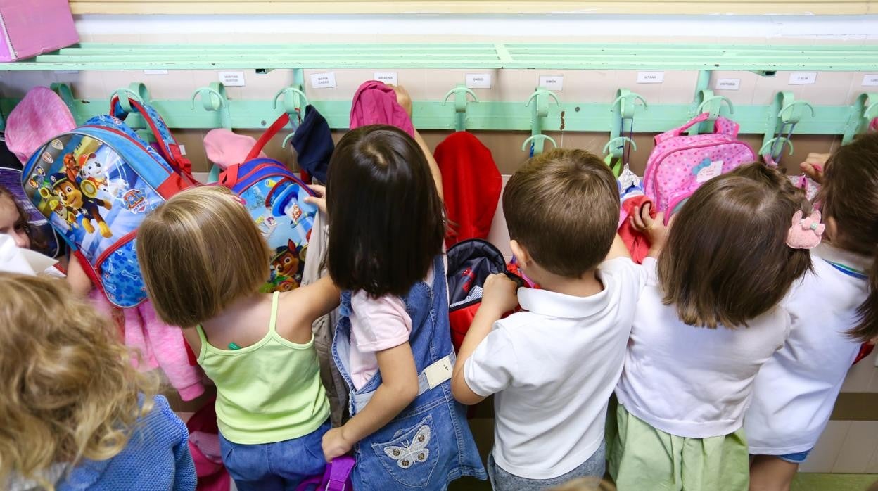 Un grupo de niños cuelga sus pertenencias en el perchero en una clase de Infantil