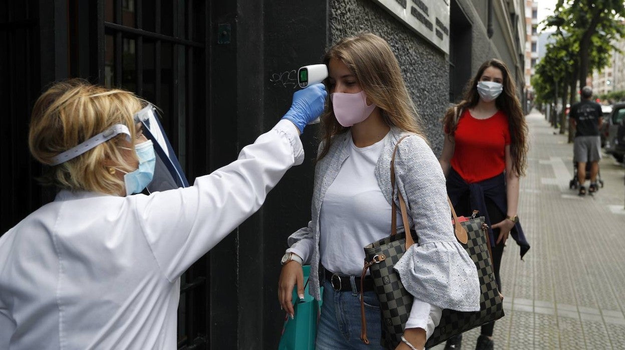 Una docente toma la temperatura a una alumna antes de entrar a clase en una imagen de archivo