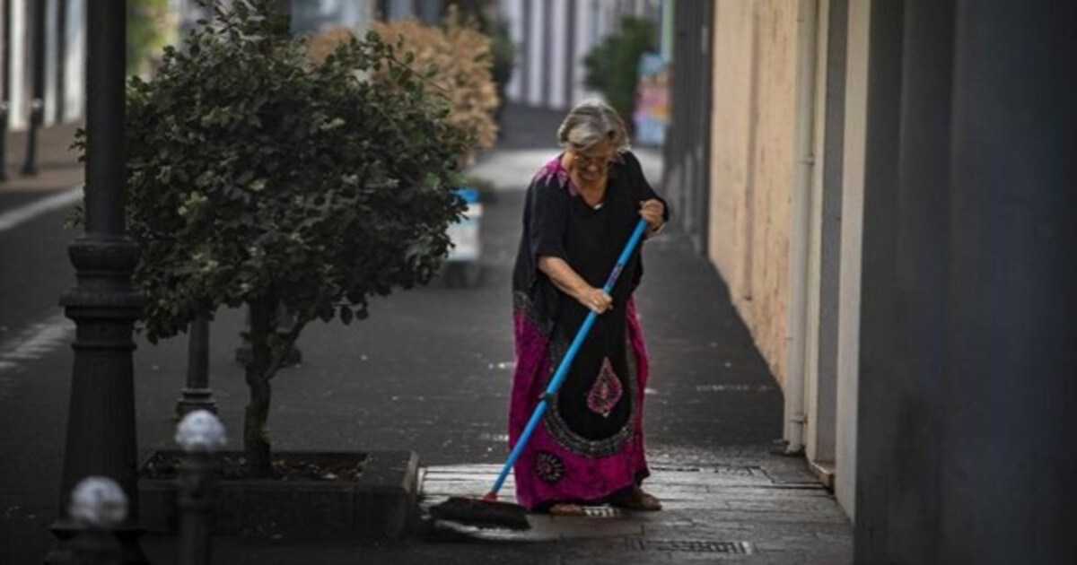 Una mujer barre la ceniza que ha llovido en Los Llanos de Aridane, una de las localidades teñidas de negro por la erupción del volcán