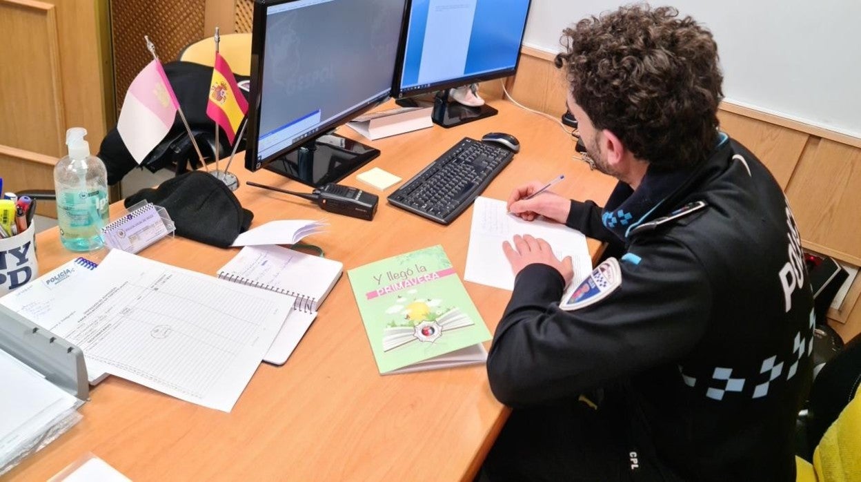 Un agente con un ejemplar, sobre la mesa, del libro «Y llegó la primavera», editado por la Policía local de Yeles con dibujos rebicidos durante la pandemia