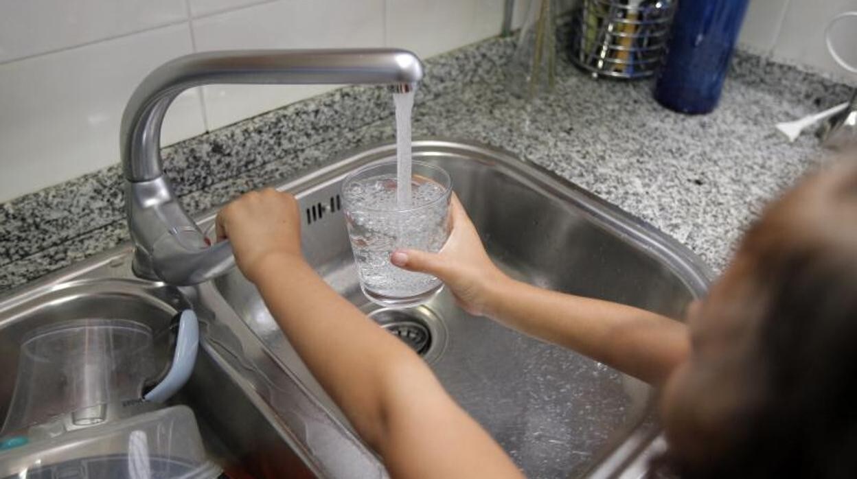 Una niña llena un vaso de agua en su casa