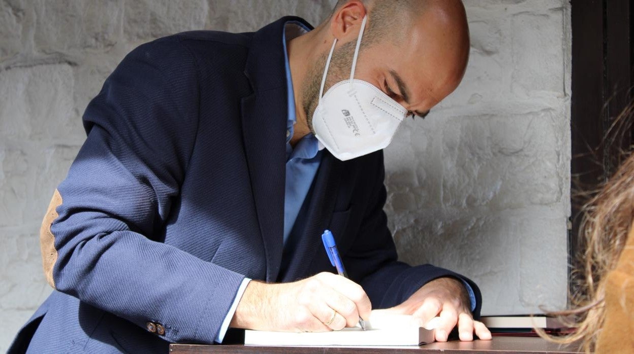 El historiador y escritor Juan Manuel Olcese firma un libro antes de la presentación de Valladolid, en la terraza del bar Naútico