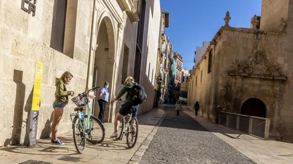 Turistas transitan por el centro de Alicante en bici y con mascarilla