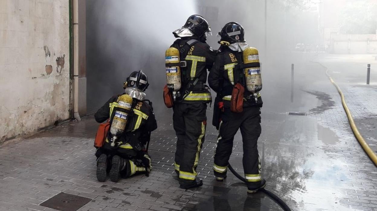 Efectivos de los Bomberos de Barcelona extinguen las llamas en un inmueble /