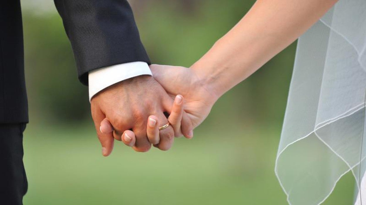 Una pareja se da la mano el día de su boda