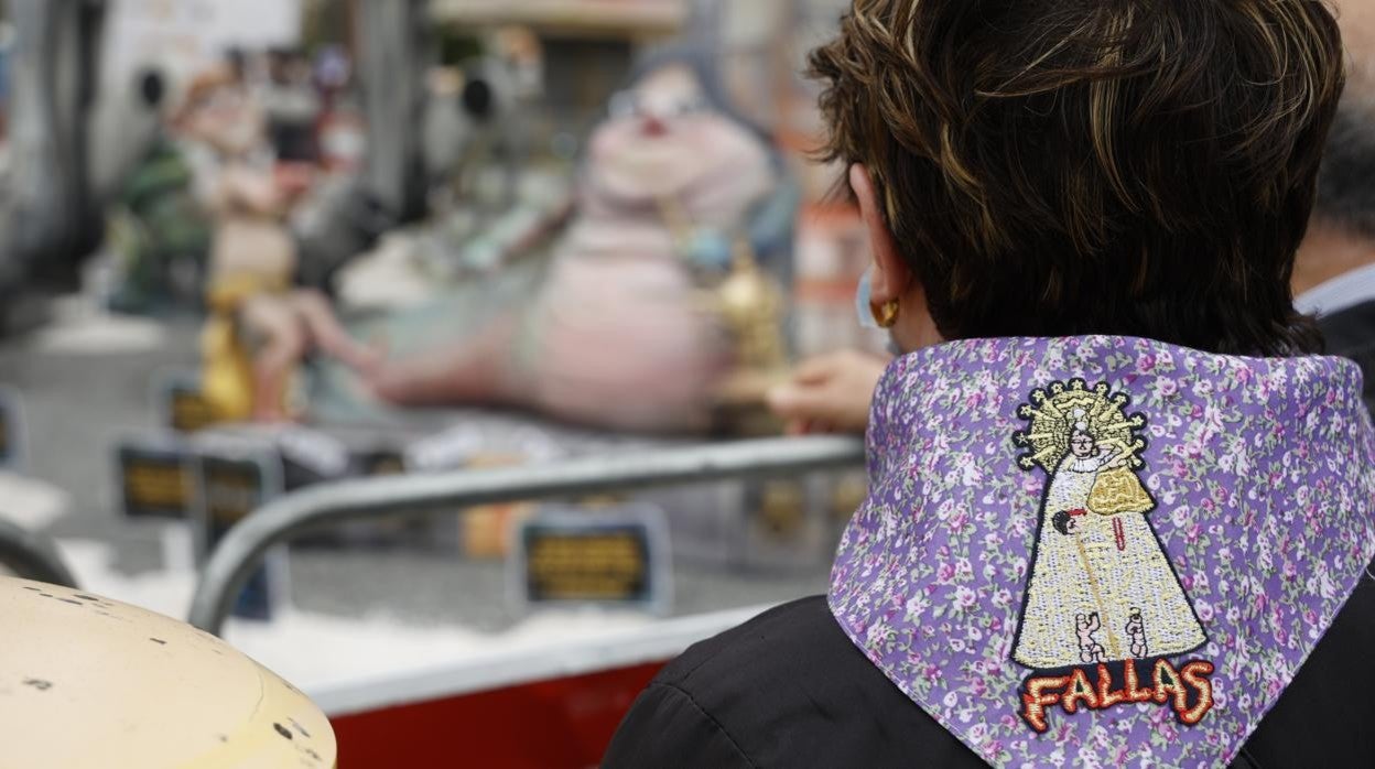 Imagen de una mujer contemplando un monumento con un pañuelo de la Virgen de los Desamparados