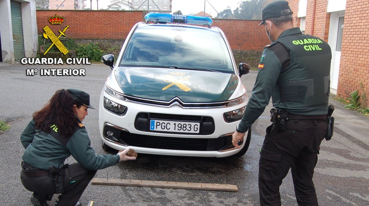 Dos agentes observan la piedra y las tablas con puntas usadas por el piquete