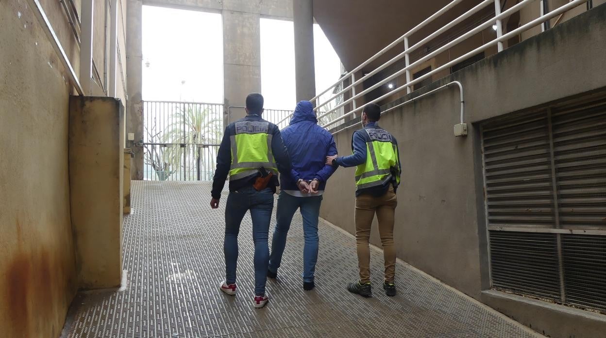 Dos agentes de la Policía Nacional flanquean al detenido en Gandía (Valencia)