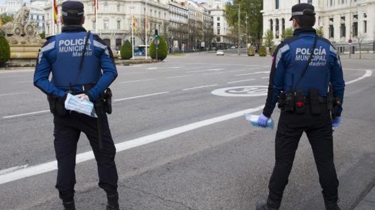 Dos policías municipales reparten mascarillas en Cibeles durante el estado de alarma