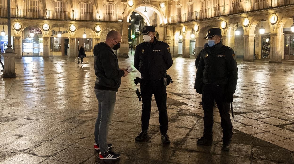 Dos agentes comprueban la documentación de un hombre que se saltó el toque de queda en Salamanca