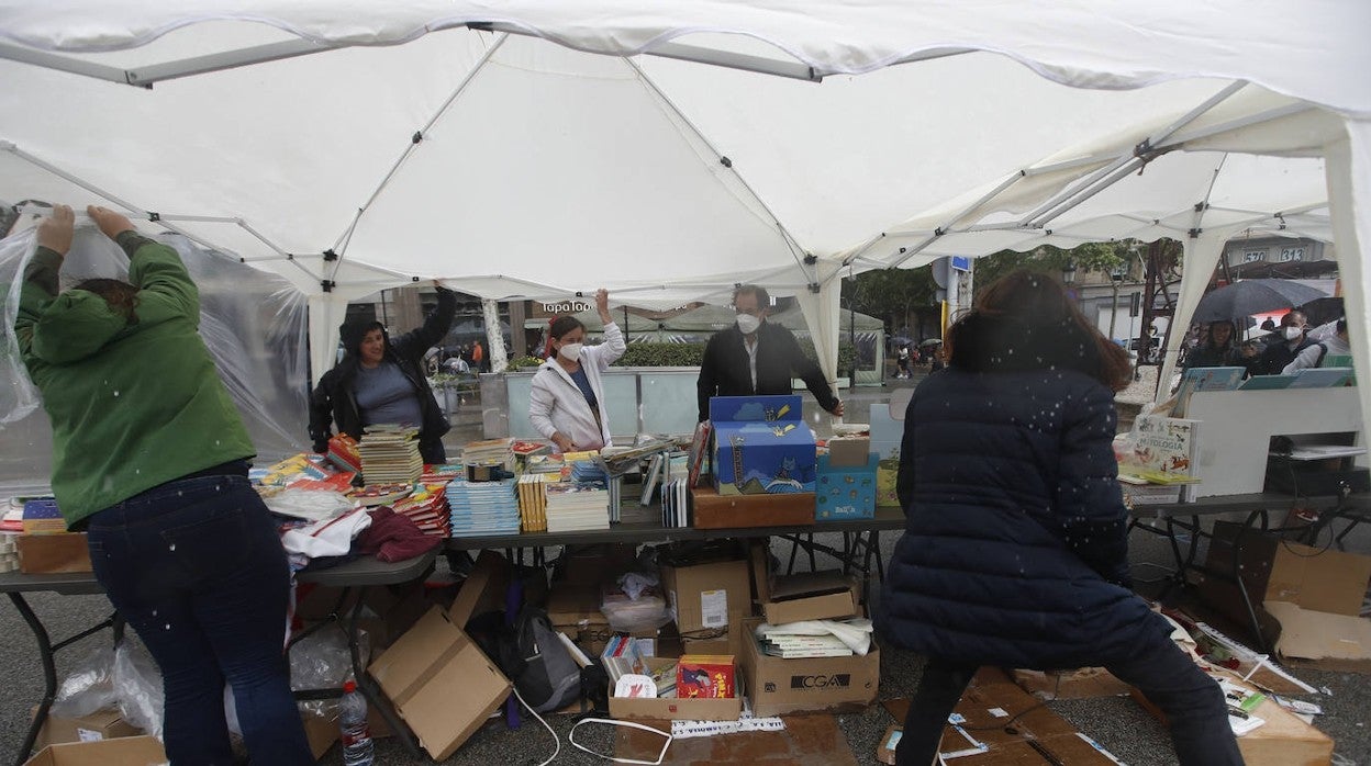 Varios libreros protegen su puesto tras la fuerte granizada caída este sábado en Barcelona