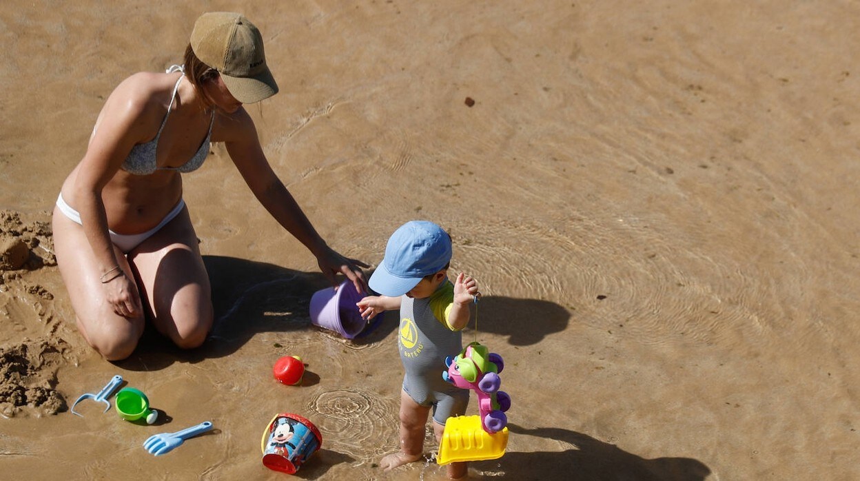 Una madre juega con su hijo en la playa de La Concha en San Sebastián