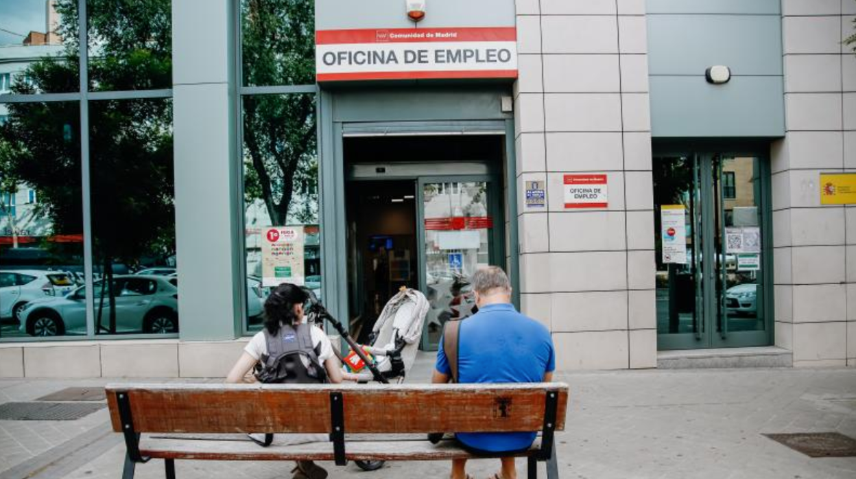 Dos personas esperan fuera de una oficina de Empleo Estatal