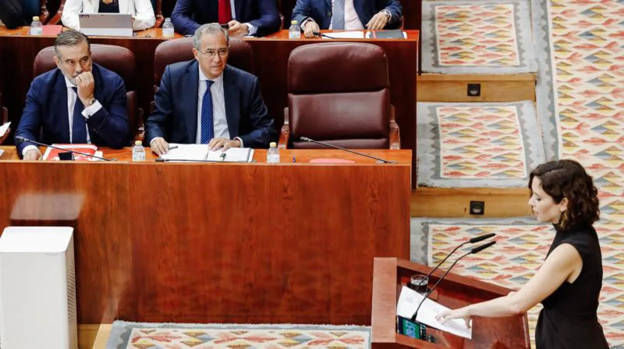 Ayuso explicando hoy en la Asamblea los cambios en su gobierno, ante la atenta mirada de Enrique López, a la izquierda, y Enrique Ossorio, a la derecha