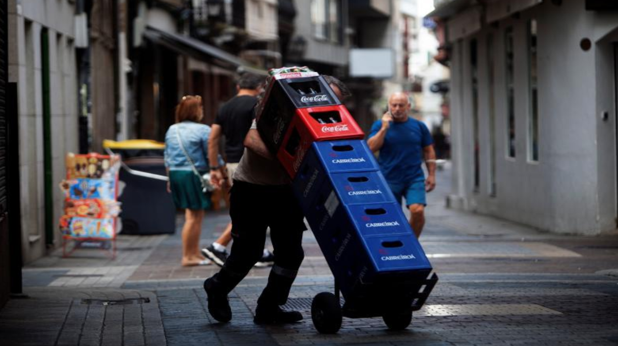 Un repartidor carga con cajas de bebidas en foto de archivo.