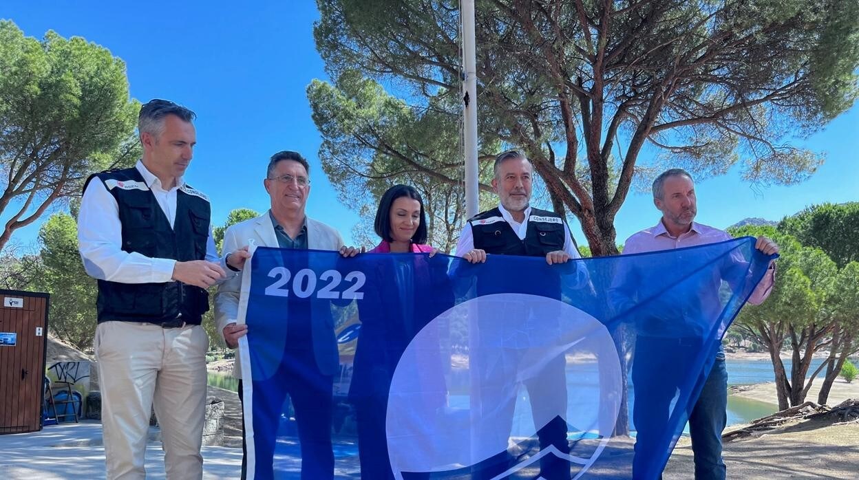 El consejero Enrique López y el viceconsejero Carlos Novillo, con los alcaldes del entorno del pantano y la bandera azul de que disfrutará su playa Virgen de la Nueva