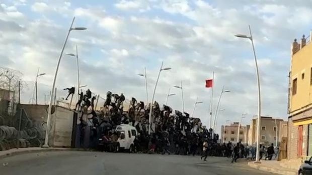 Captura del vídeo en el que se ve a los inmigrantes tratando de saltar la valla de acceso al melillense Barrio Chino momentos antes de que cediera