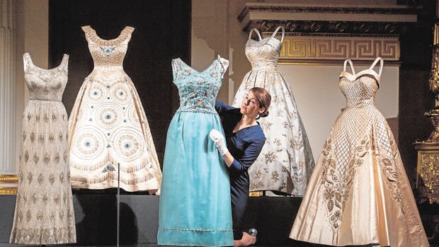 Una empleada da los últimos retoques a uno de los vestidos expuestos en el Palacio de Buckingham