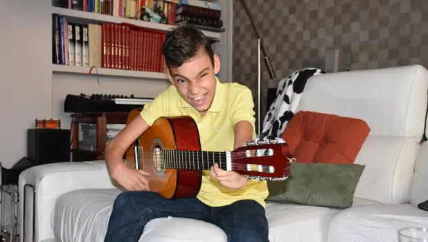 Adrián en el salón de su casa con su guitarra
