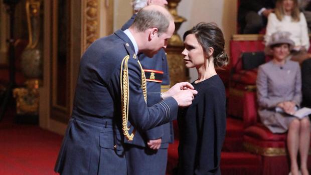 El príncipe Guillermo coloca la condecoración a Victoria Beckham