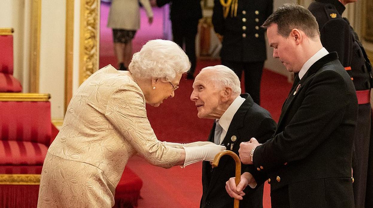 La Reina Isabel II condecora al veterano del Día D Harry Billinge.