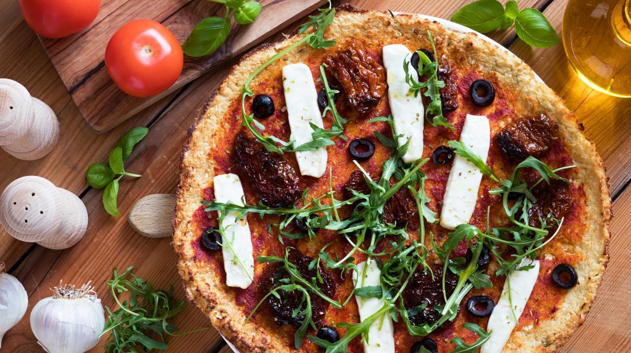 Pizza con base de coliflor y con tomates cherry.