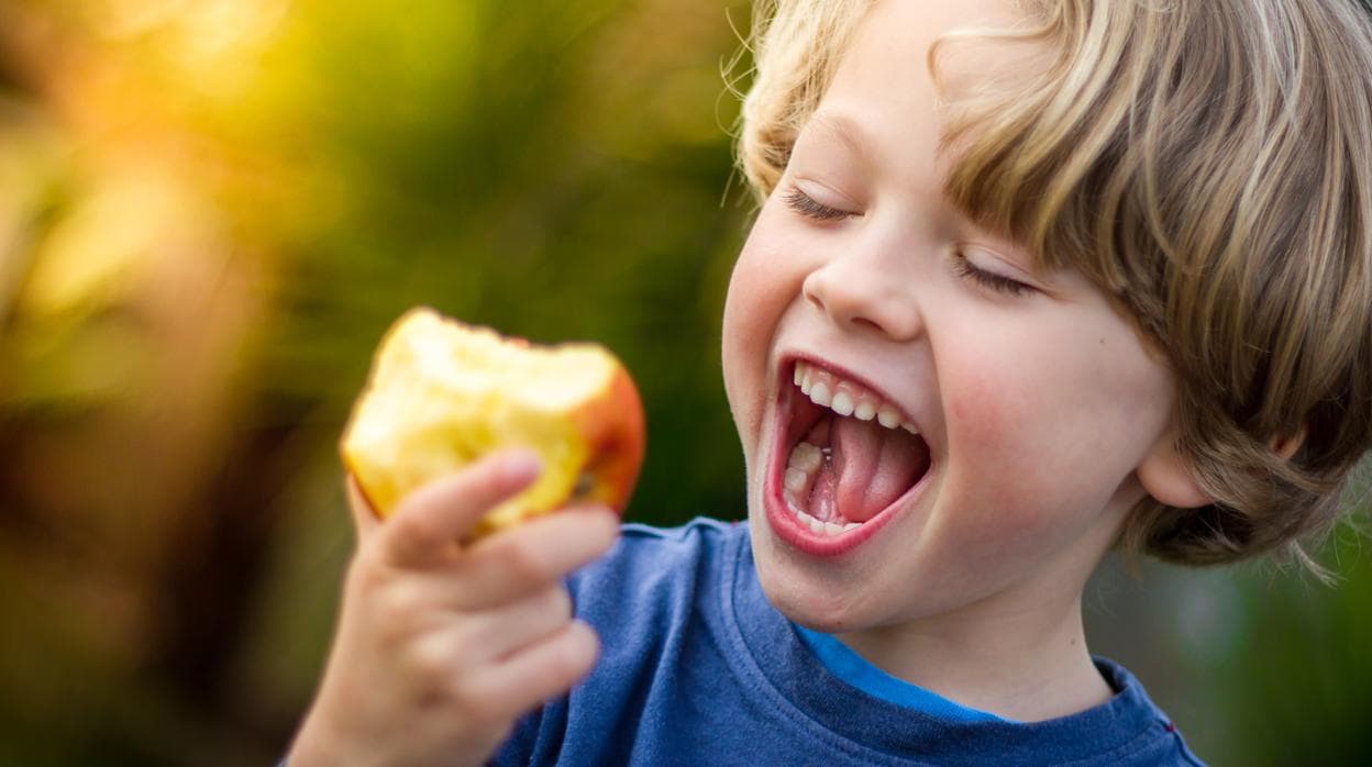 Un niño, comiendo una manzana.
