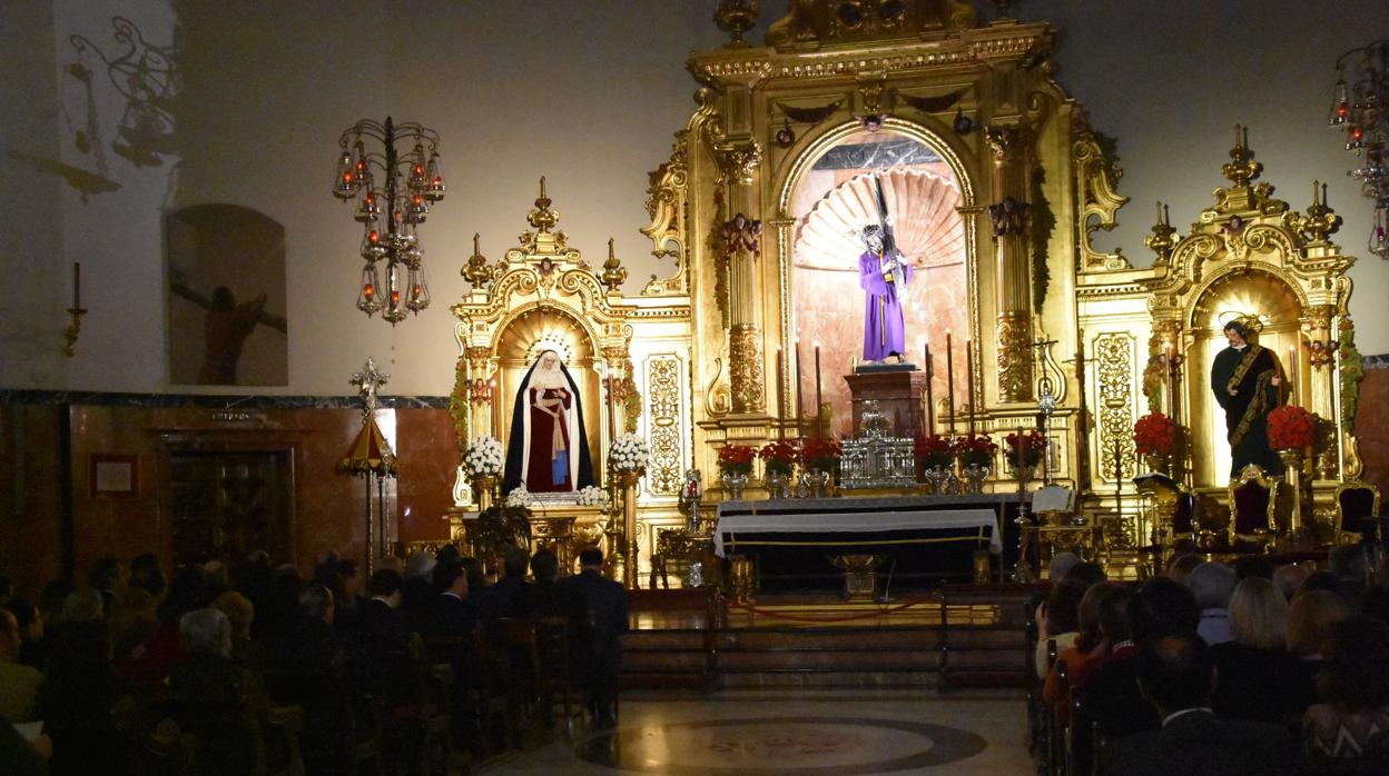 A oscuras, sólo con la luz de los cirios que iluminan al Señor de Sevilla