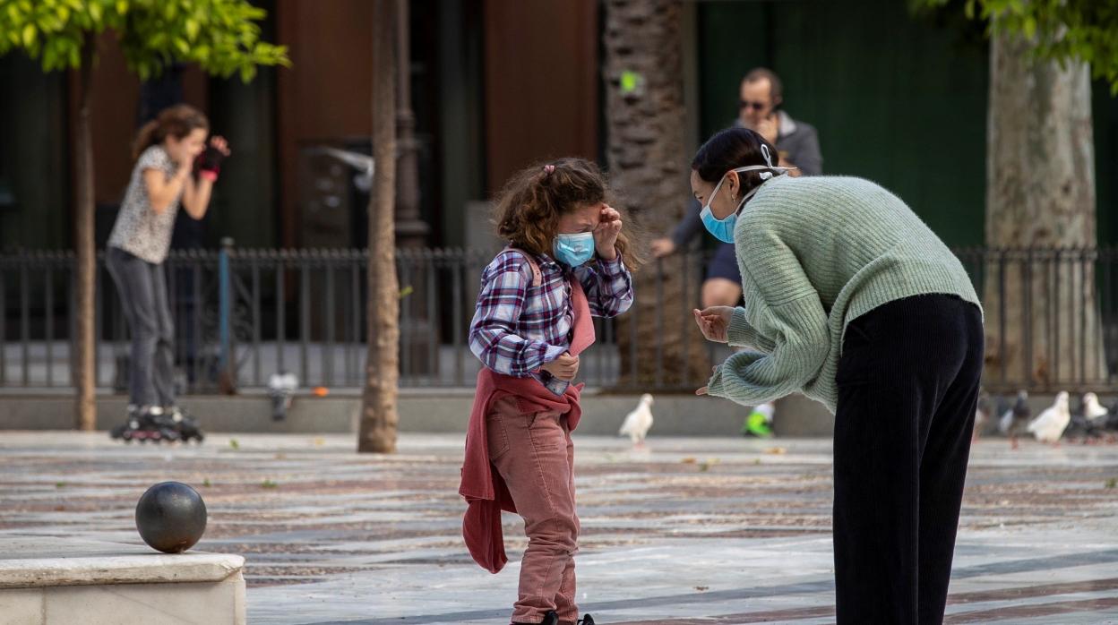 Una niña en patines y con mascarilla en la Plaza Nueva de Sevilla