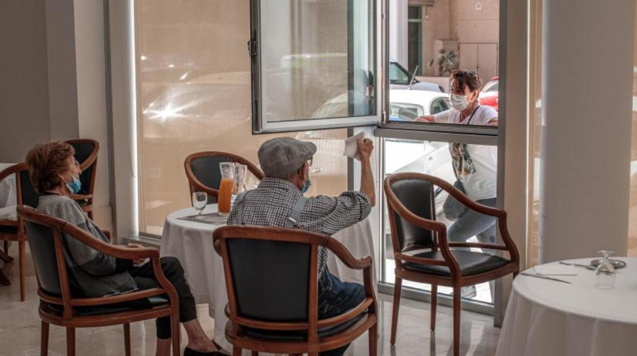 Una persona conversa con sus padres a través de una ventana habilitada en la residencia de mayores Ballesol Patacona, en Valencia