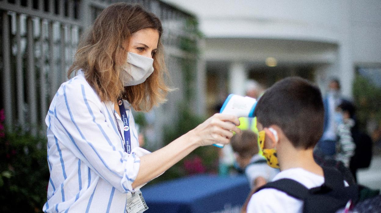 Una trabajadora toma la temperatura a un niño a la entrada del colegio privado internacional American School of Barcelona