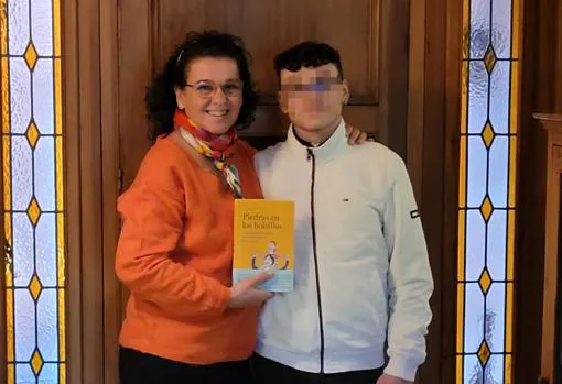 Marta feliz, junto a su hijo que hoy tiene 17 años, muestra el libro con toda su experiencia