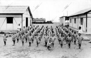 Colonia veraniega practicando ejercicios de gimnasia a las órdenes del profesor