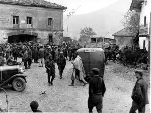 Soldados navarros, paisanos y mulas, junto a un vehículo de la Cruz Roja, en el...