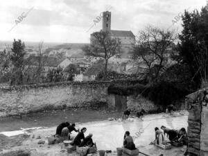 En la imagen, mujeres lavando la ropa y al fondo una de las torres antiquísimas...