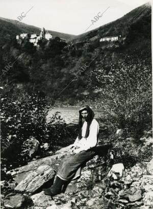 Una mujer posa en las Fragas del Eume con el Monasterio de Caaveiro al fondo