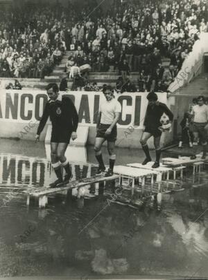 Los jugadores y equipo arbitral hubieron de utilizar unos improvisados «puentes»...