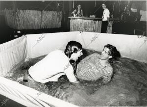 En la imagen dos asistentes a la fiesta, se remojan en una piscina colocada en...