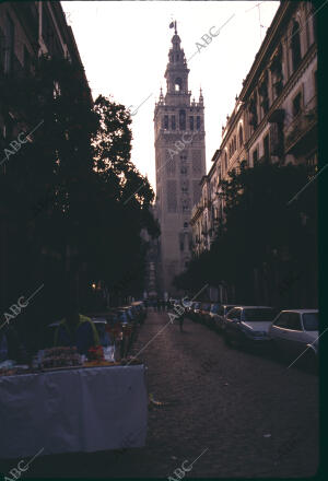 Calle de Sevilla en la que se aprecia la Giralda y un puesto con dulces