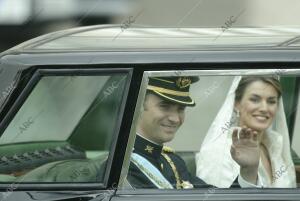 Los recién casados, sonrientes, responden con un saludo a las aclamaciones de...