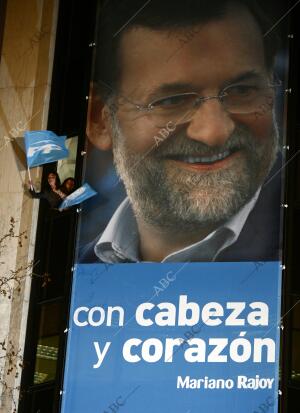 Mariano Rajoy y su equipo saludan desde el balcón de la sede del PP después de...